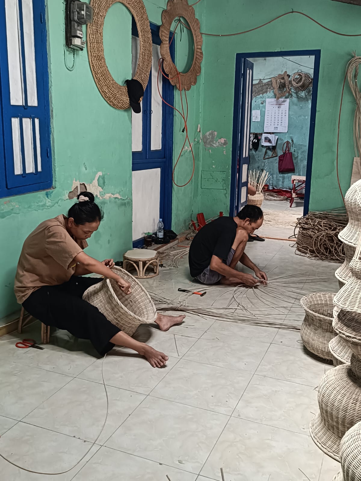 Tangan pengrajin sedang menganyam rotan
